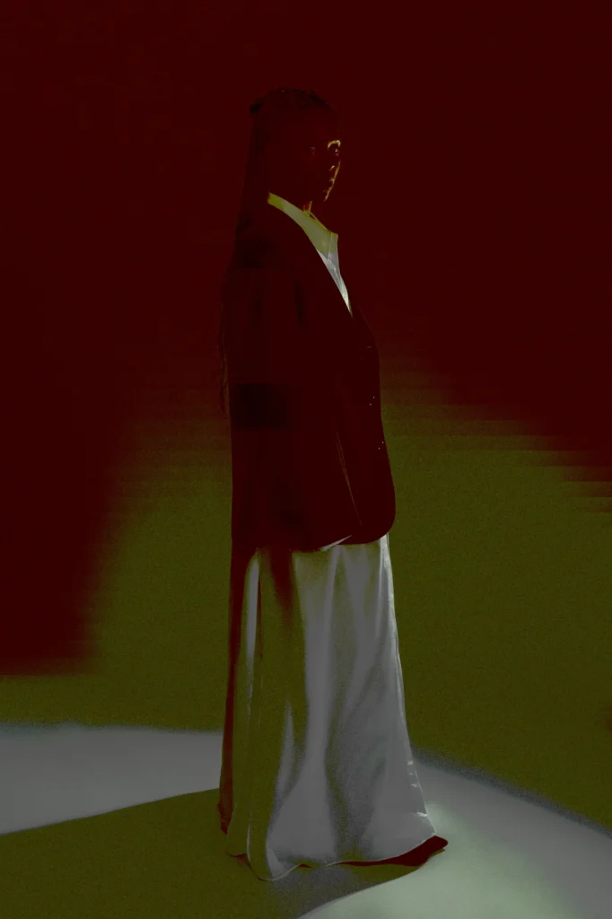 Woman in profile wearing red blazer over white silk maxi skirt, dramatic red lighting, Berlin fashion portrait