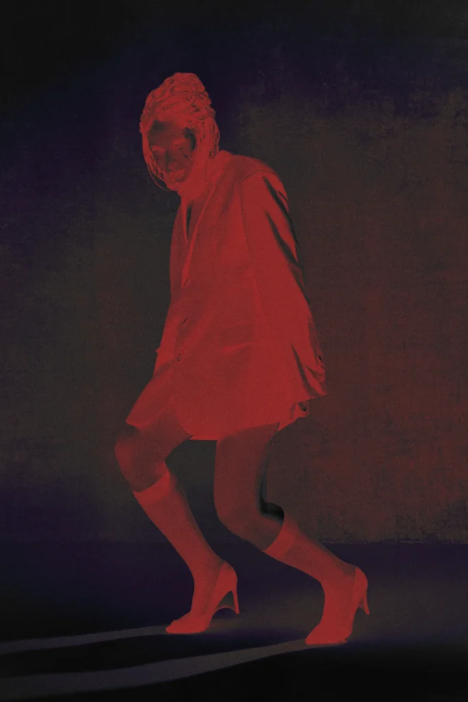 Model in oversized blazer and heels with artistic red lighting, avant-garde fashion editorial berlin