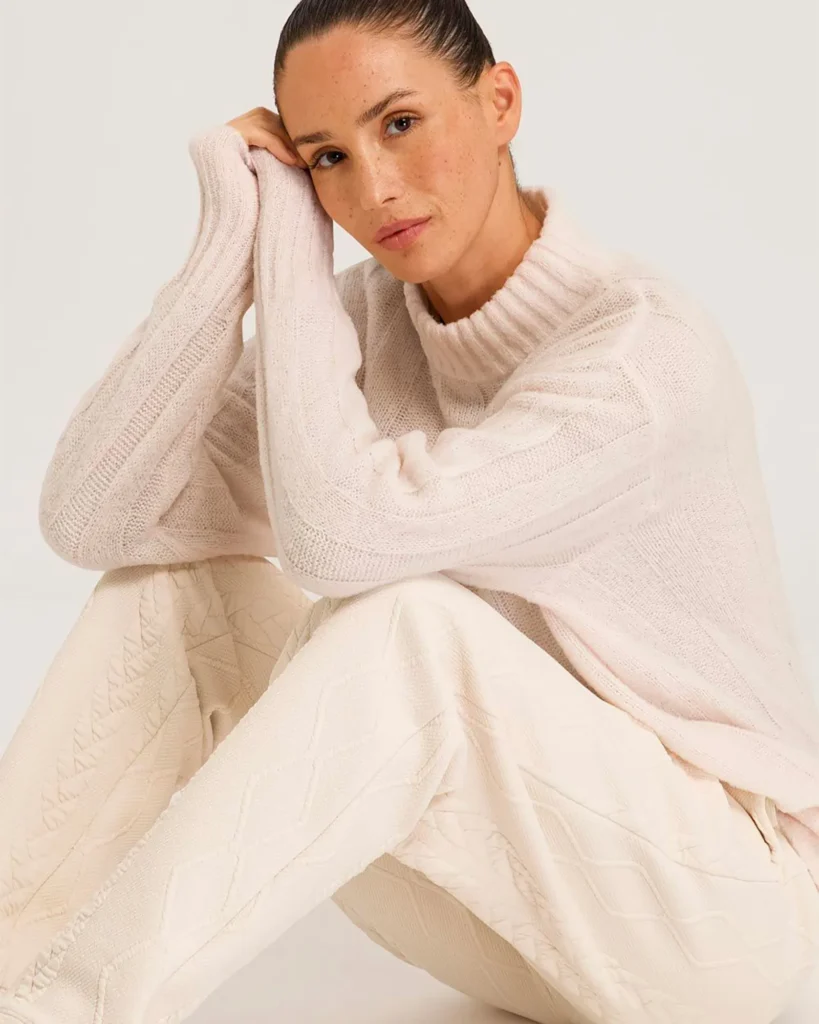 Woman in soft pink turtleneck sweater and cream knit pants, minimal studio fashion portrait Berlin