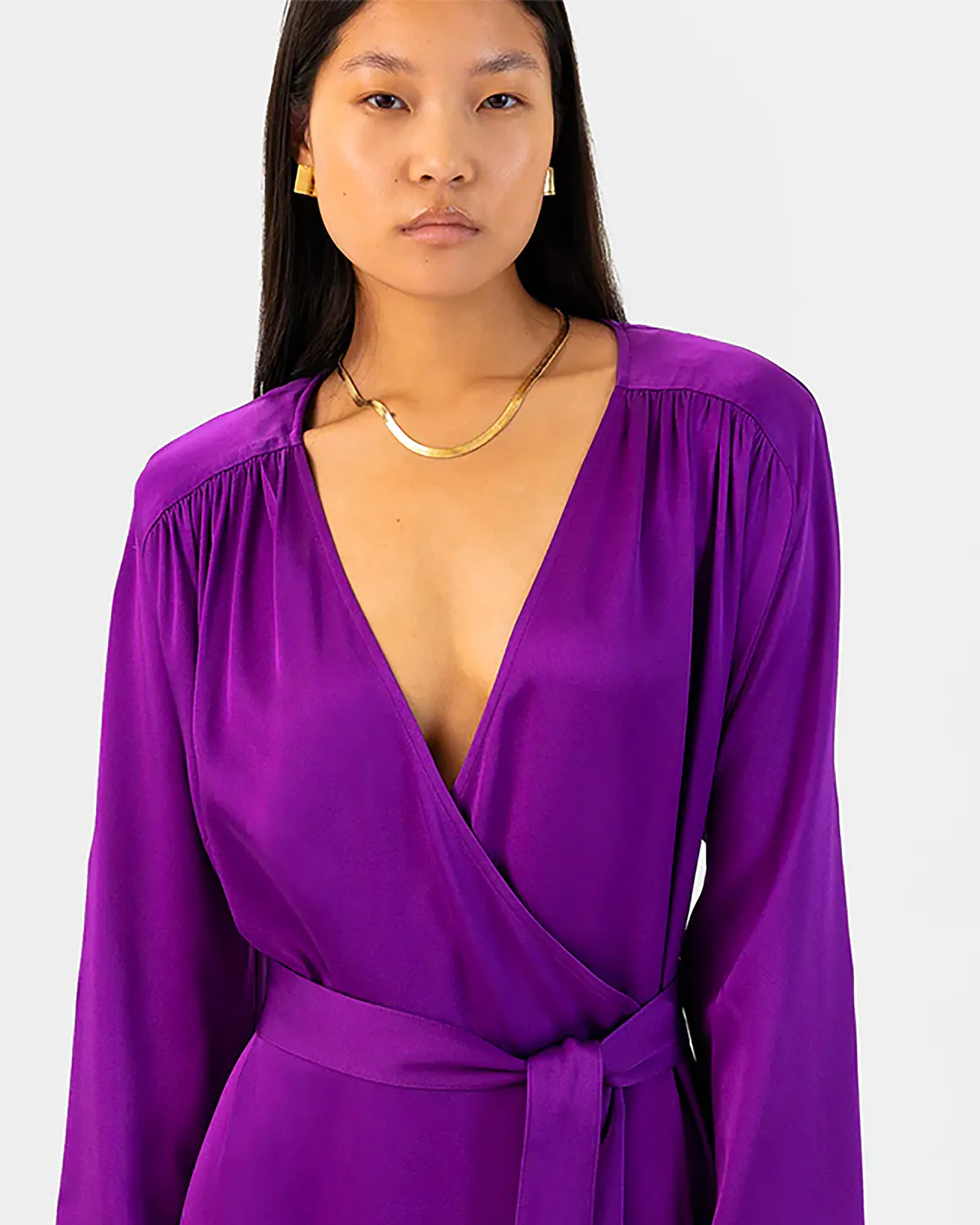 Asian model wearing vibrant purple silk wrap dress with gold jewelry, Berlin fashion photography